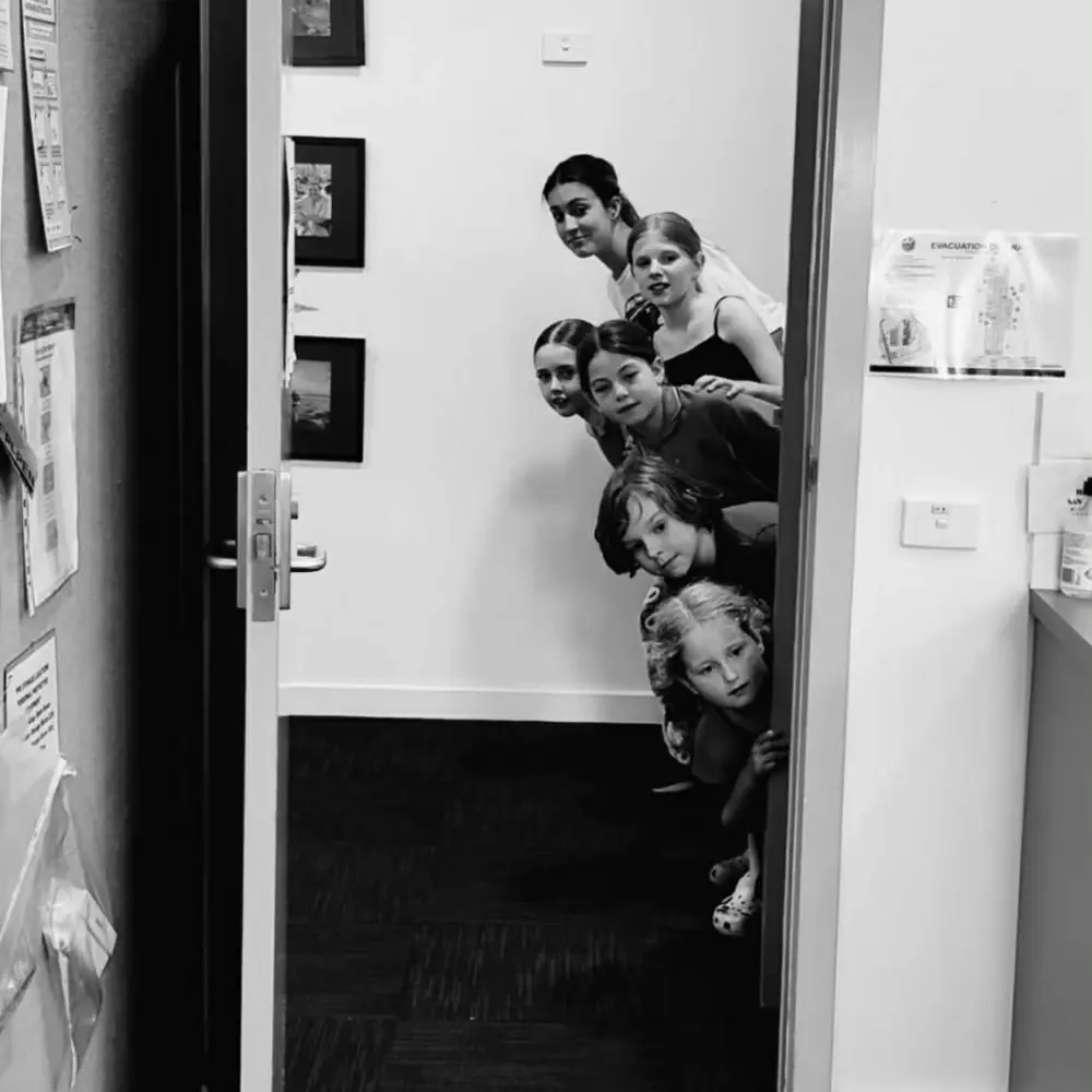childrens drama class. Kids poking their heads around the door in black and white